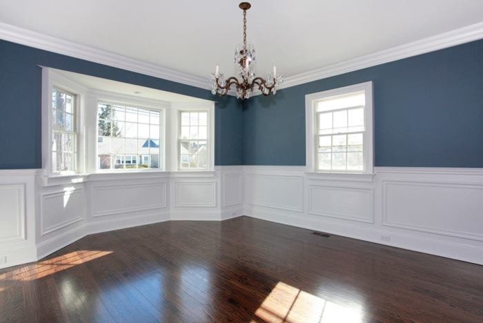 Cette photo montre une salle à manger chic fermée et de taille moyenne avec un mur bleu, un sol en bois brun et aucune cheminée.