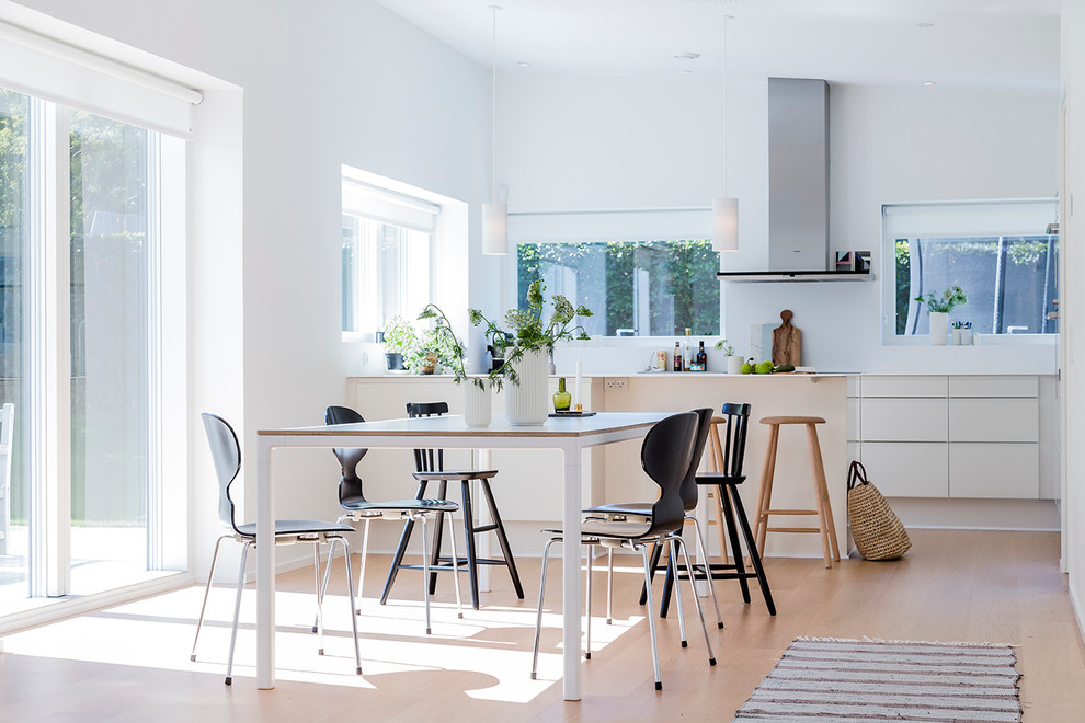 Foto di una sala da pranzo aperta verso la cucina scandinava di medie dimensioni con pareti bianche, parquet chiaro e nessun camino