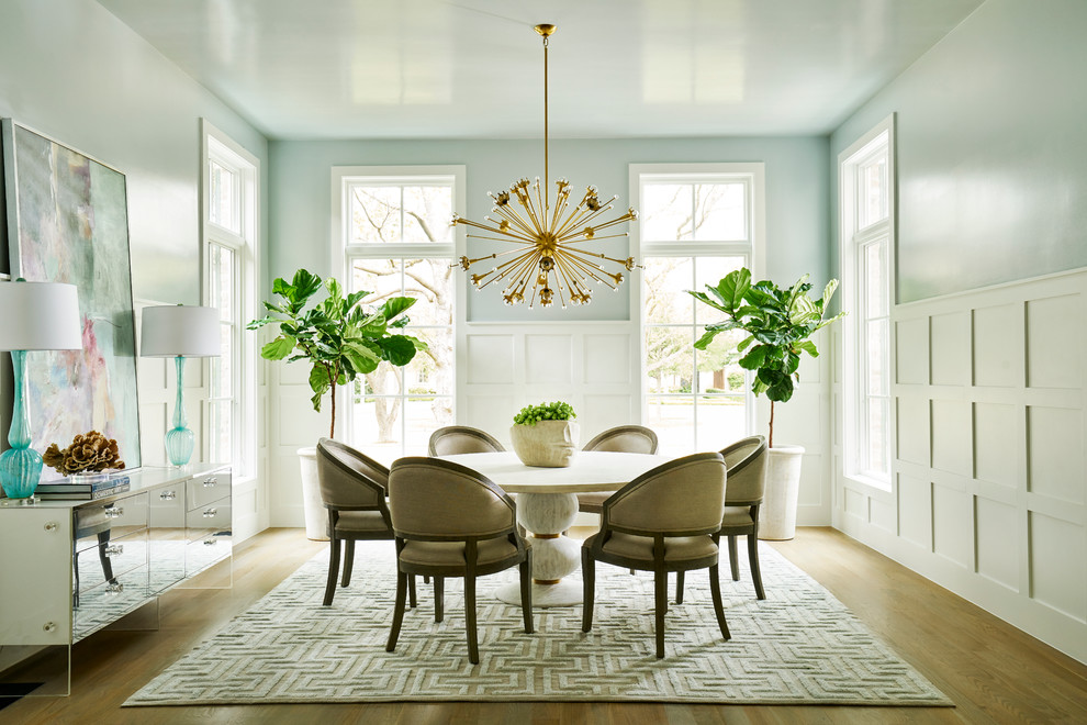 Exemple d'une salle à manger chic avec un mur bleu, parquet clair et éclairage.