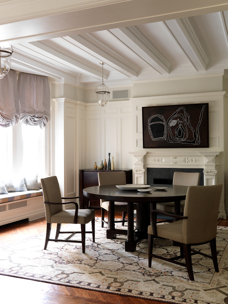 Idée de décoration pour une salle à manger tradition avec un mur blanc, un sol en bois brun, une cheminée standard et un manteau de cheminée en pierre.