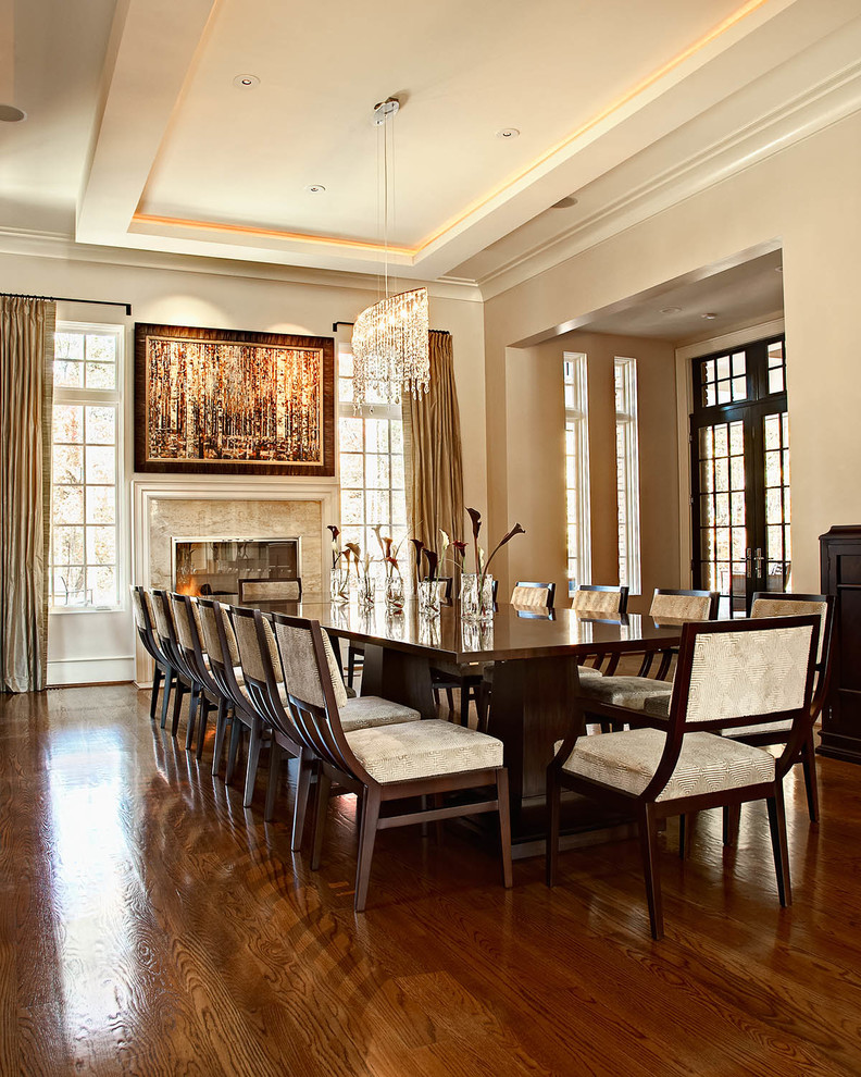 Immagine di una sala da pranzo tradizionale con pareti beige, parquet scuro e camino classico