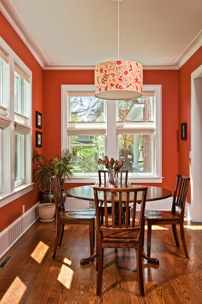 Imagen de comedor clásico pequeño cerrado con parades naranjas y suelo de madera en tonos medios