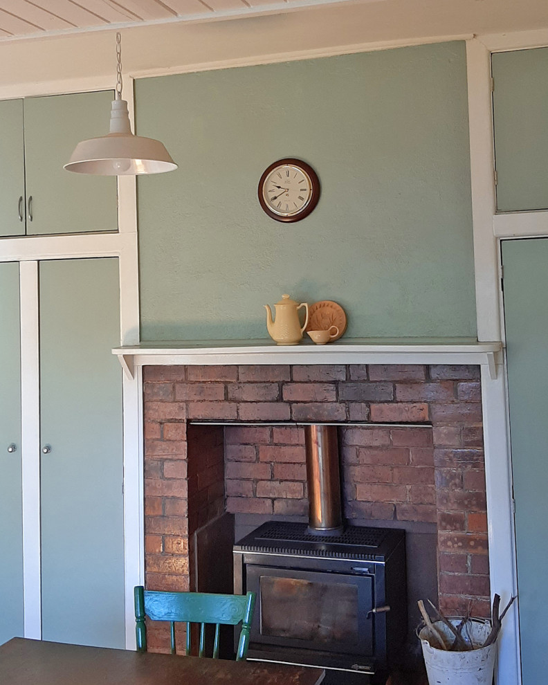 Cette photo montre une petite salle à manger ouverte sur la cuisine nature avec un mur vert, parquet clair, une cheminée standard, un manteau de cheminée en brique, un plafond en bois et du lambris de bois.