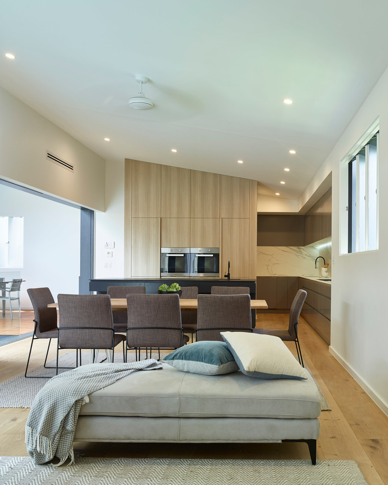 Offenes Modernes Esszimmer mit beiger Wandfarbe, hellem Holzboden und beigem Boden in Brisbane