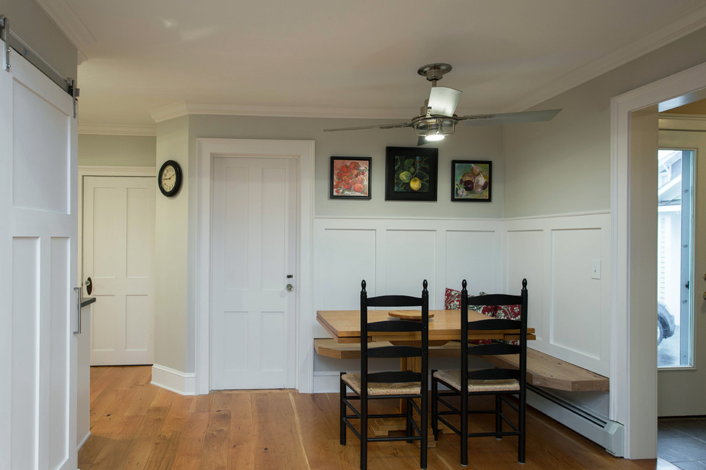 Cette photo montre une salle à manger ouverte sur la cuisine chic de taille moyenne avec un sol en bois brun, un mur gris et aucune cheminée.