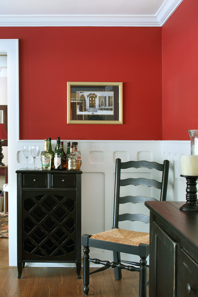 Imagen de comedor clásico de tamaño medio cerrado con paredes rojas, suelo de madera en tonos medios, todas las chimeneas y marco de chimenea de yeso