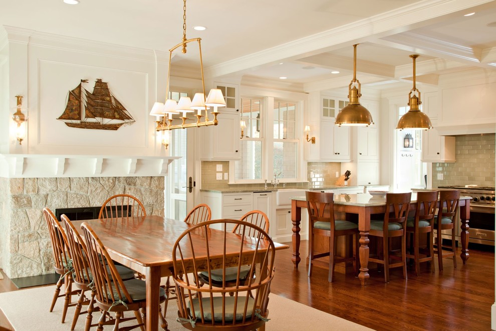 Exemple d'une salle à manger ouverte sur la cuisine bord de mer avec un mur blanc, parquet foncé, une cheminée standard et un manteau de cheminée en pierre.
