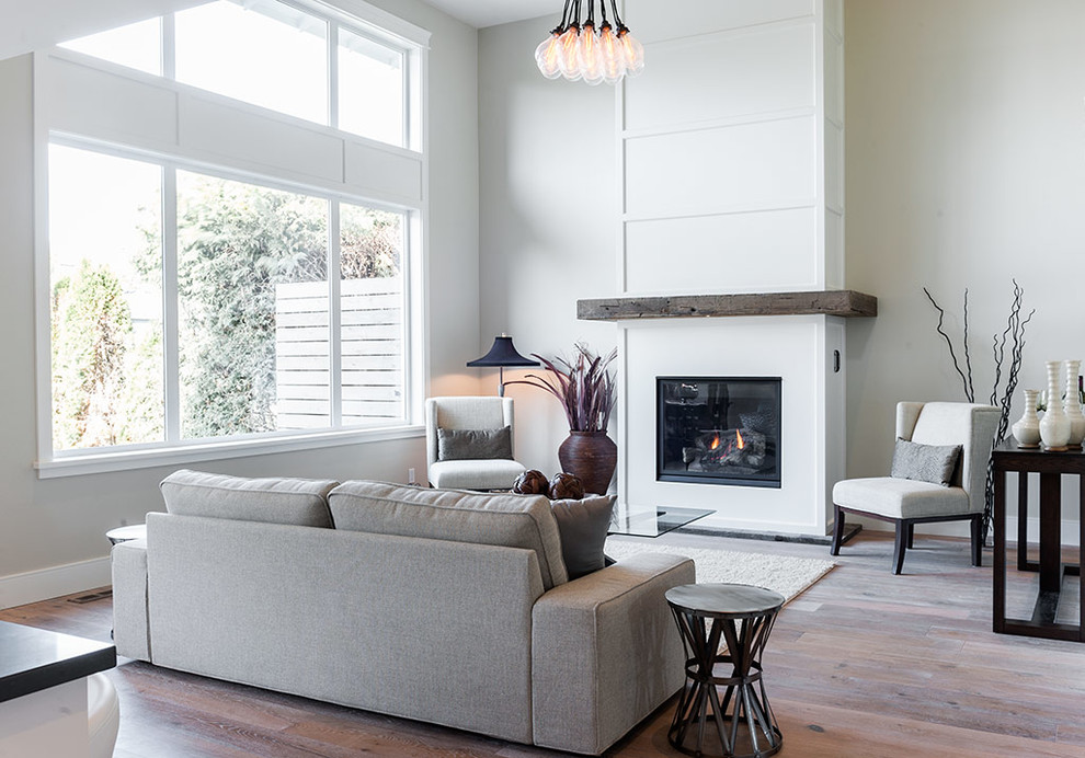 Inspiration for a large modern medium tone wood floor and brown floor great room remodel in Vancouver with white walls, a standard fireplace and a wood fireplace surround