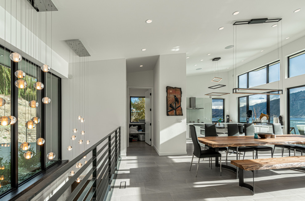 Immagine di una grande sala da pranzo aperta verso la cucina moderna con pareti bianche, pavimento in gres porcellanato e pavimento grigio