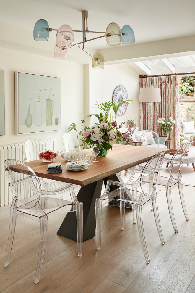 Inspiration pour une salle à manger ouverte sur le salon bohème de taille moyenne avec un mur beige, parquet clair et éclairage.