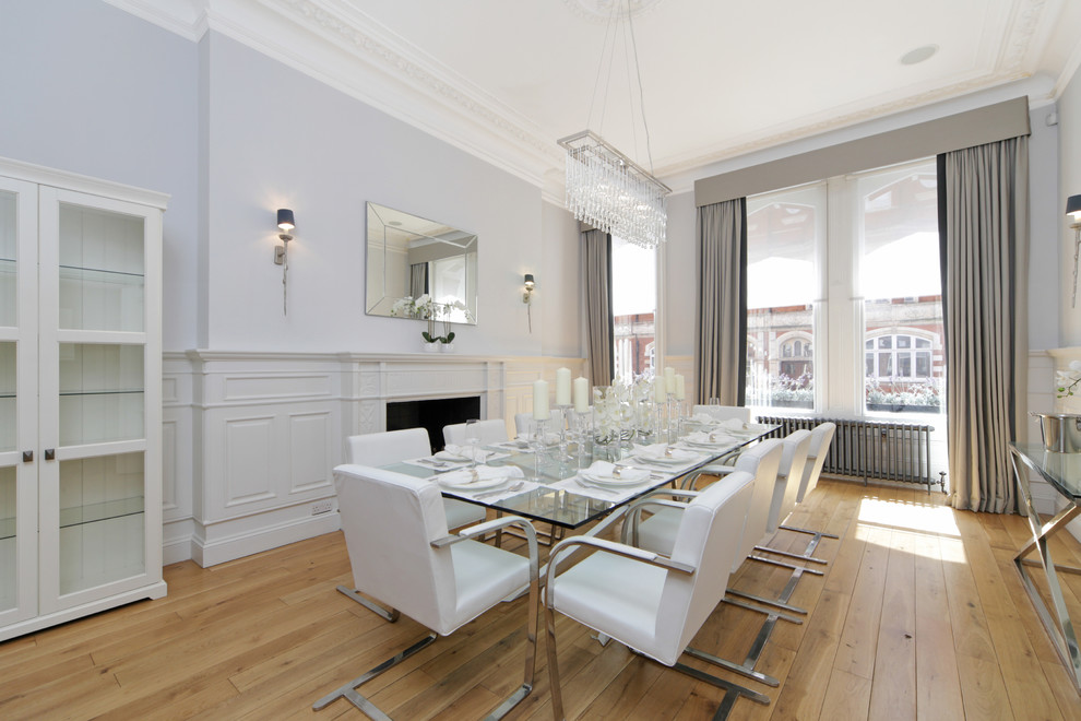 Cette photo montre une salle à manger chic fermée et de taille moyenne avec parquet clair, une cheminée standard, un sol beige et un mur gris.