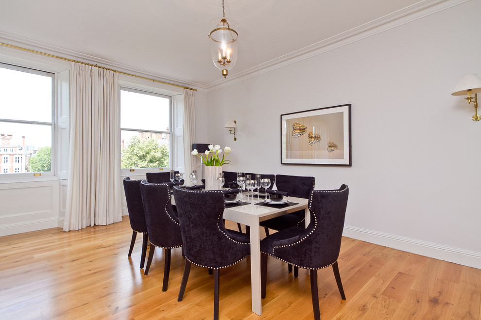 Imagen de comedor contemporáneo con paredes blancas, suelo de madera en tonos medios y cortinas