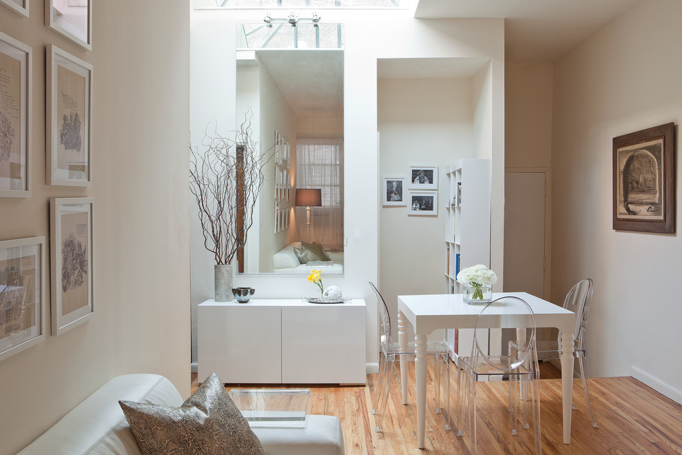 Inspiration pour une salle à manger minimaliste avec un mur blanc, un sol en bois brun et éclairage.