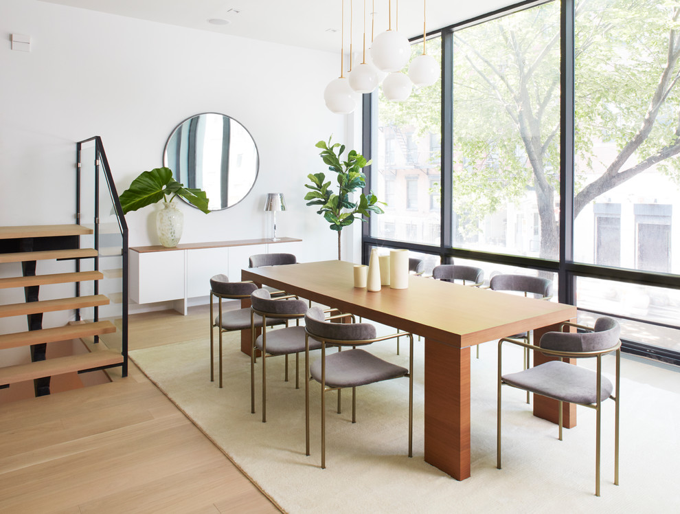 Immagine di una sala da pranzo contemporanea con pareti bianche, parquet chiaro e pavimento beige