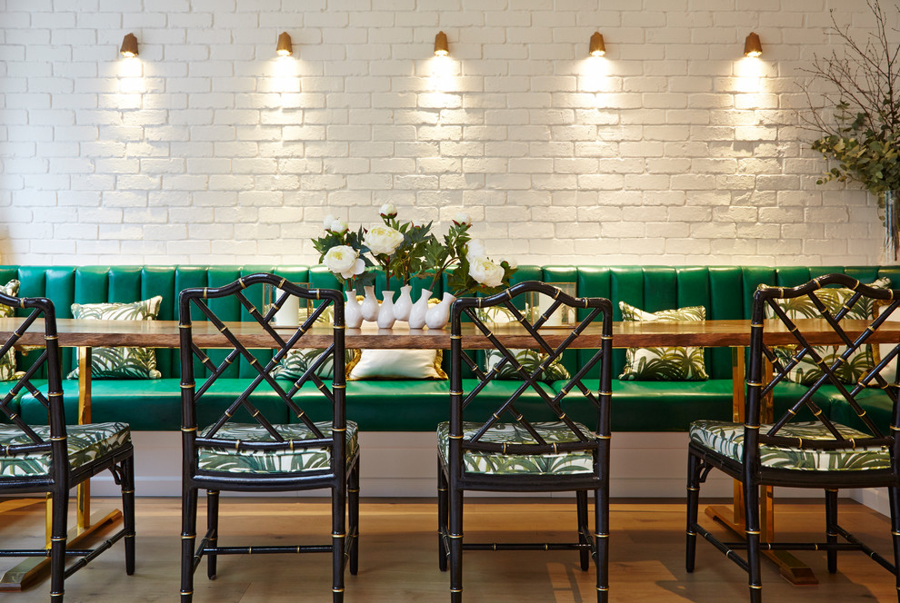 Cette photo montre une salle à manger tendance avec un mur blanc et un sol en bois brun.
