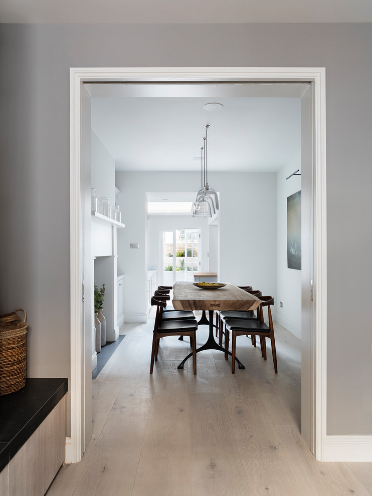 Réalisation d'une salle à manger ouverte sur la cuisine design de taille moyenne avec un mur blanc, parquet clair et un sol blanc.