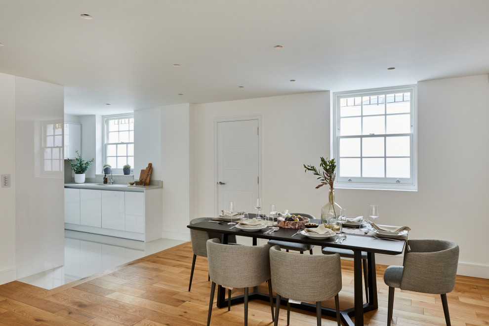 Photo of a medium sized modern open plan dining room in London with white walls, medium hardwood flooring and brown floors.
