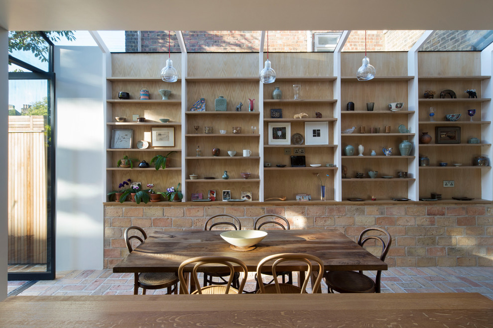 Cette image montre une salle à manger nordique de taille moyenne avec un mur marron, un sol en brique et un sol orange.