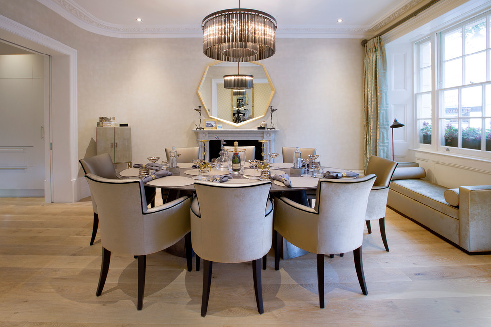 Dining room - contemporary light wood floor dining room idea in London with beige walls, a standard fireplace and a stone fireplace
