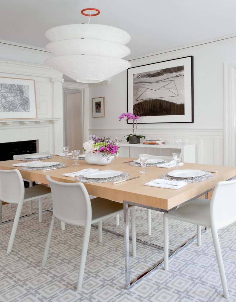 Стильный дизайн: столовая в современном стиле с белыми стенами и стандартным камином - последний тренд