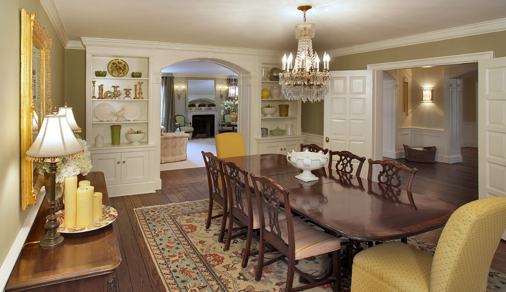 Aménagement d'une grande salle à manger ouverte sur la cuisine victorienne avec un mur vert et un sol en bois brun.