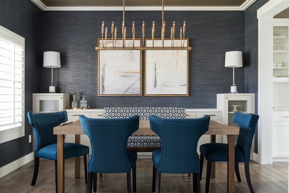 Cette image montre une salle à manger marine fermée avec un mur bleu, aucune cheminée, un sol en bois brun et éclairage.