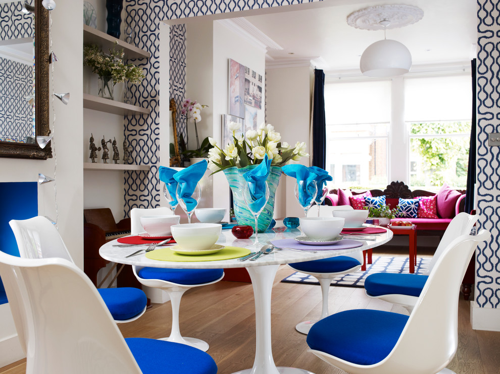 Inspiration pour une salle à manger design fermée et de taille moyenne avec un mur multicolore, parquet clair et un manteau de cheminée en plâtre.