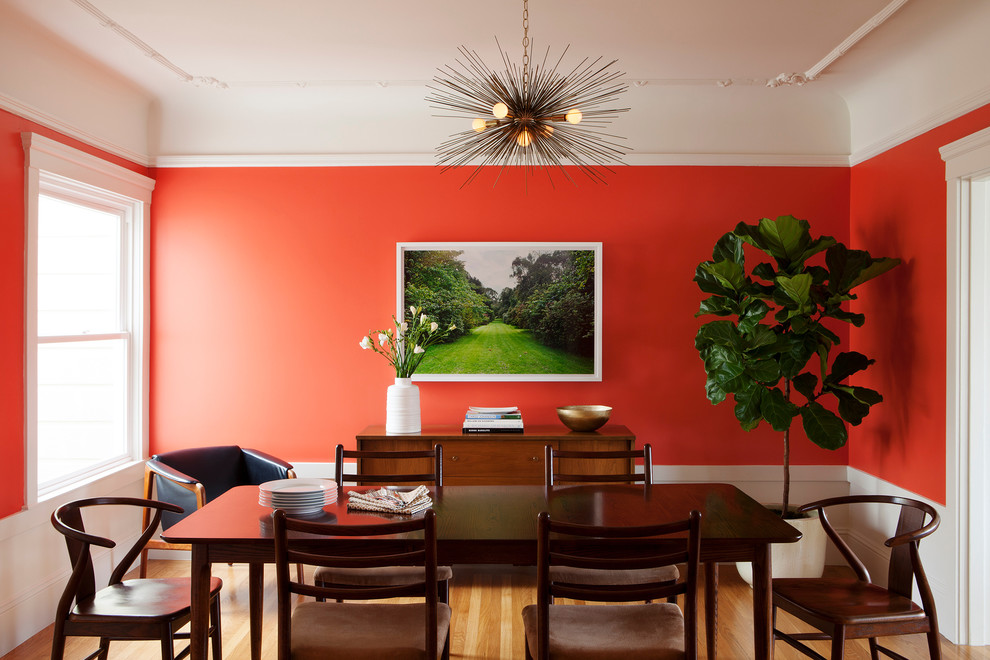 На фото: отдельная столовая в стиле неоклассика (современная классика) с оранжевыми стенами и паркетным полом среднего тона без камина