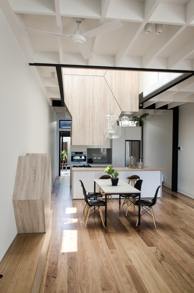 Idee per una sala da pranzo aperta verso la cucina design con pareti bianche, pavimento in legno massello medio e pavimento marrone