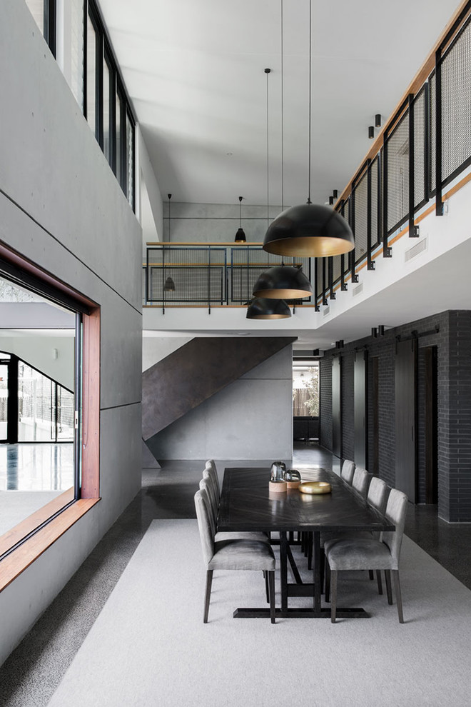 Cette photo montre une salle à manger ouverte sur le salon industrielle avec un mur gris, sol en béton ciré et un sol gris.