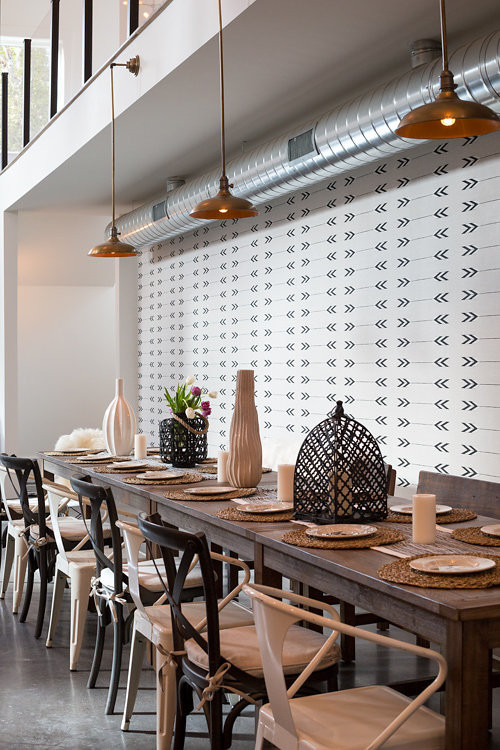 Idée de décoration pour une grande salle à manger ouverte sur la cuisine urbaine avec un mur beige, sol en béton ciré, une cheminée ribbon et un manteau de cheminée en métal.