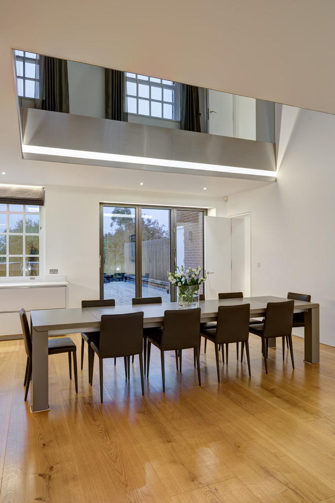 Large modern open plan dining room in London with white walls, light hardwood flooring and no fireplace.
