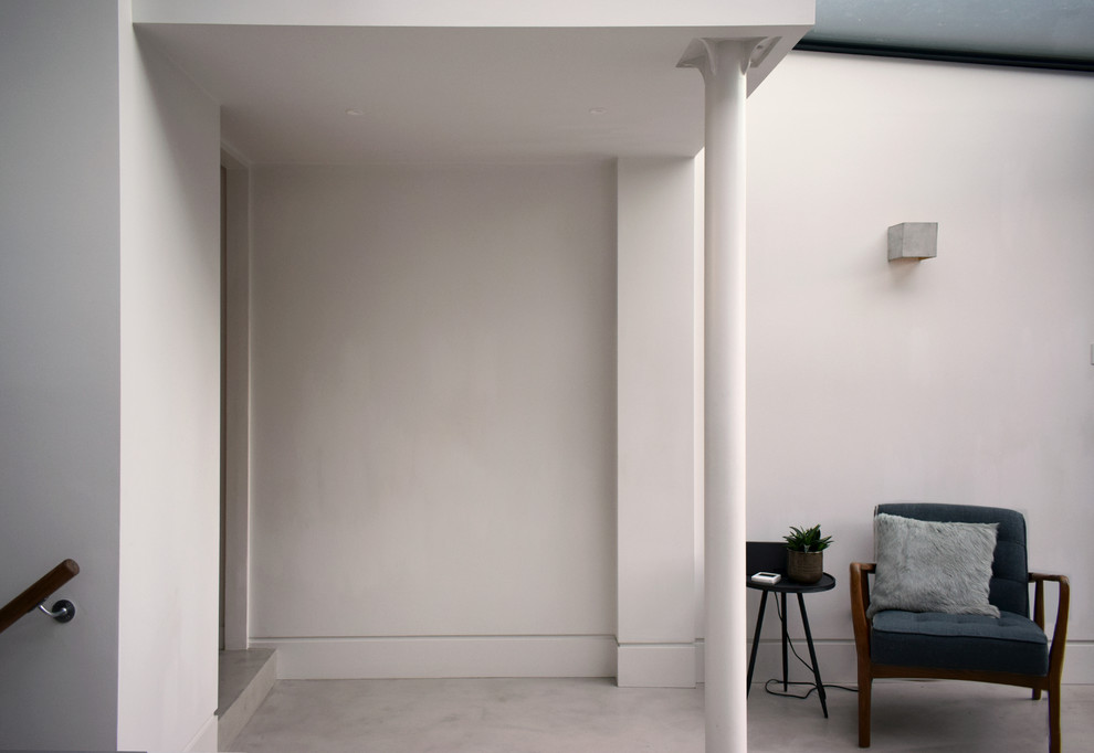 Esempio di una sala da pranzo aperta verso la cucina moderna di medie dimensioni con pareti bianche, pavimento in cemento e pavimento grigio