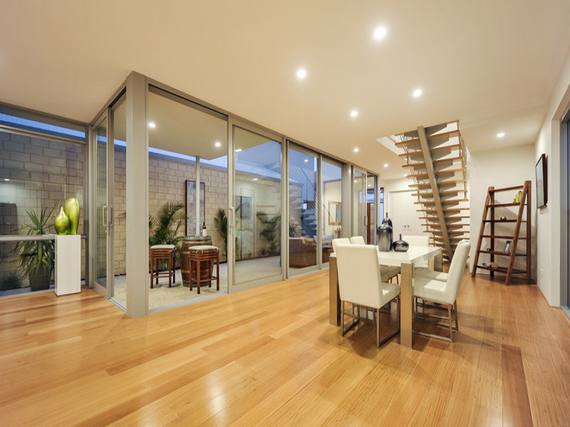 This is an example of an expansive contemporary kitchen/dining room in Perth with white walls and light hardwood flooring.