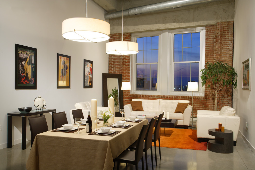 Cette photo montre une salle à manger ouverte sur le salon industrielle avec un mur blanc et sol en béton ciré.