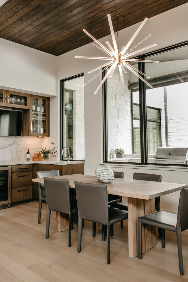 Immagine di una grande sala da pranzo aperta verso la cucina contemporanea con pareti bianche, pavimento beige e pareti in legno