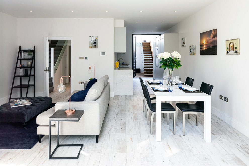 Photo of a medium sized contemporary open plan dining room in London with white walls, white floors and painted wood flooring.