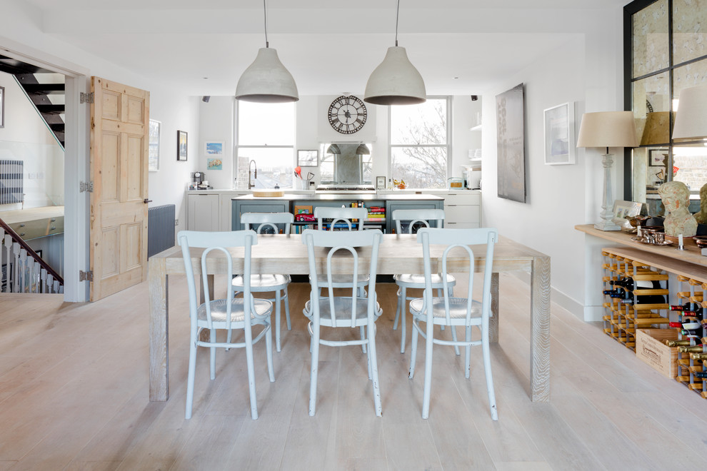 This is an example of a medium sized coastal kitchen/dining room in London with white walls, light hardwood flooring and no fireplace.