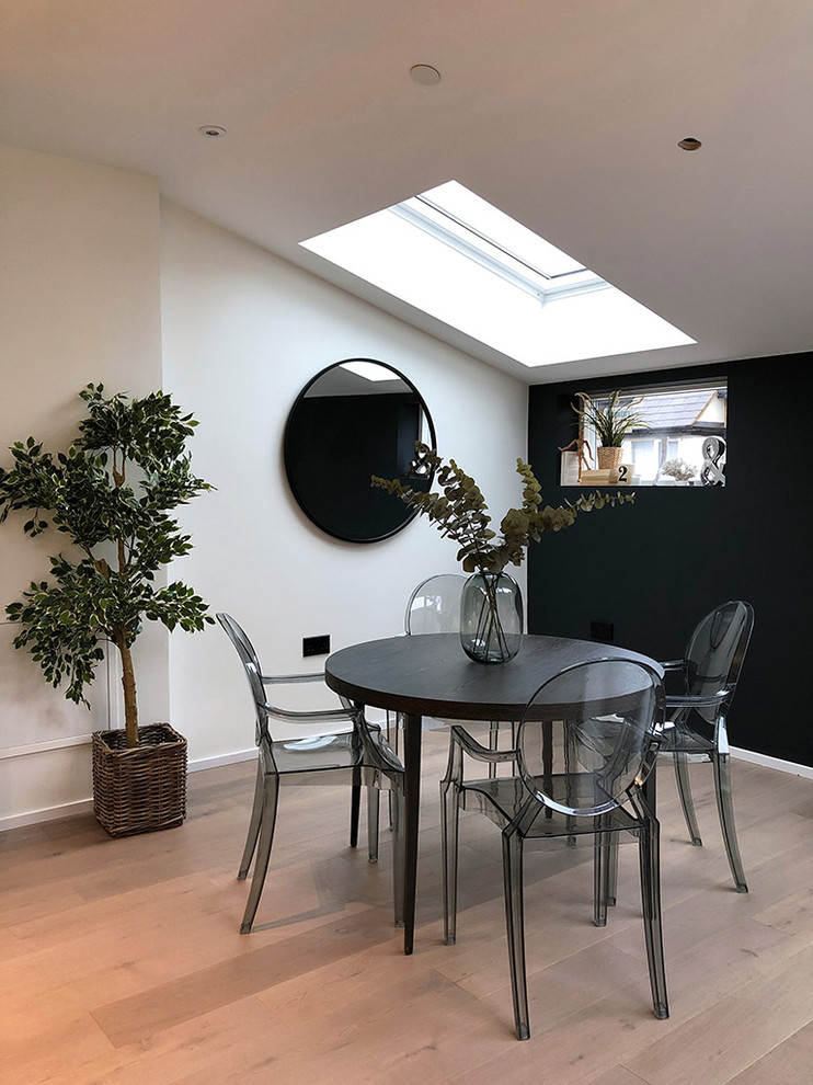 Inspiration pour une salle à manger ouverte sur le salon minimaliste de taille moyenne avec un mur noir, parquet clair, aucune cheminée et un sol beige.