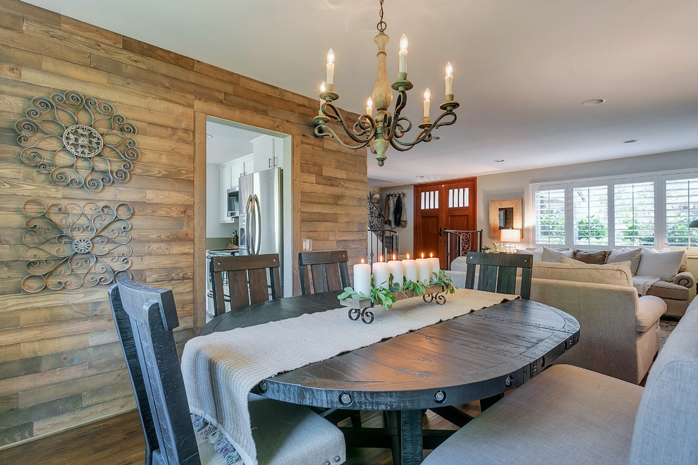 Cette image montre une salle à manger ouverte sur le salon chalet de taille moyenne avec un mur gris, un sol en bois brun et aucune cheminée.