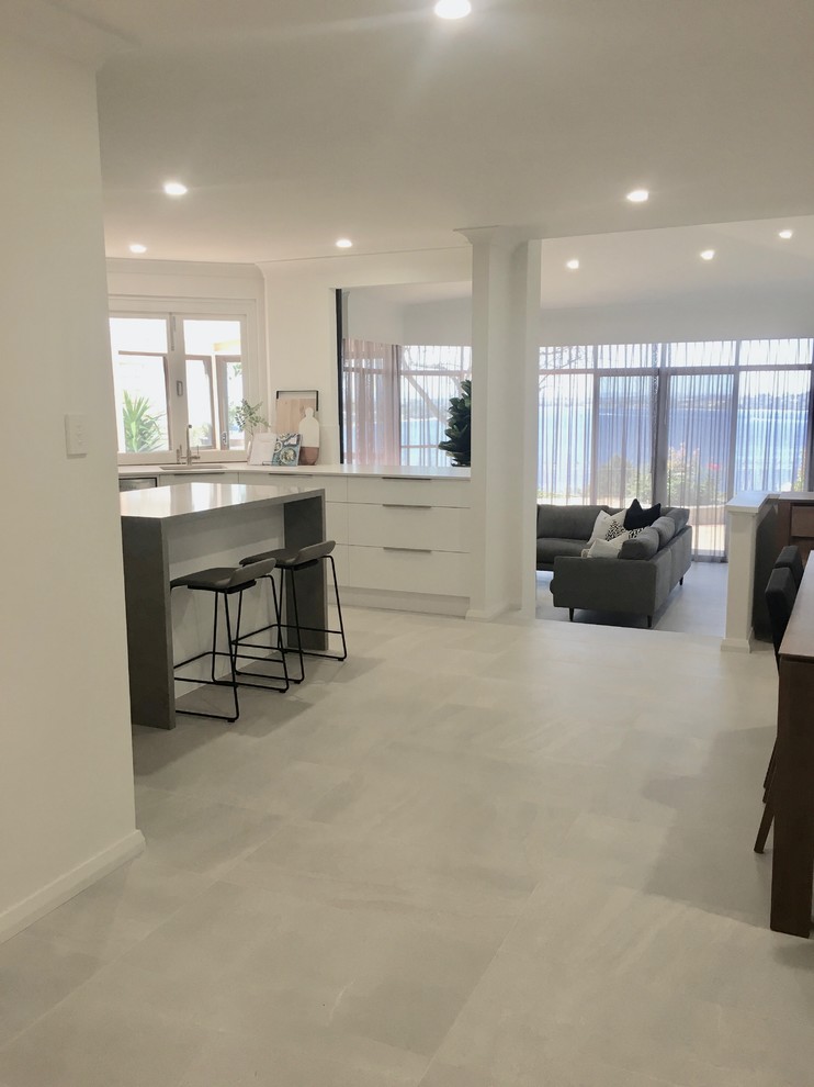 Immagine di una sala da pranzo aperta verso il soggiorno minimal di medie dimensioni con pareti bianche, pavimento in gres porcellanato e pavimento grigio