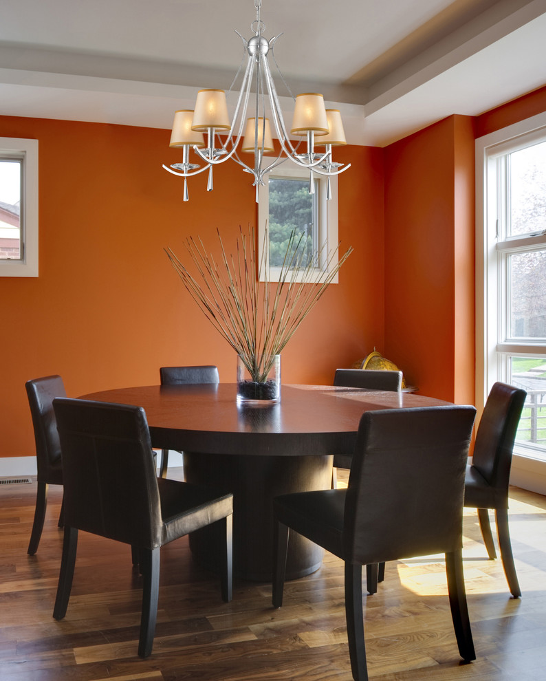 Пример оригинального дизайна: большая отдельная столовая в стиле неоклассика (современная классика) с оранжевыми стенами, паркетным полом среднего тона, стандартным камином и фасадом камина из камня