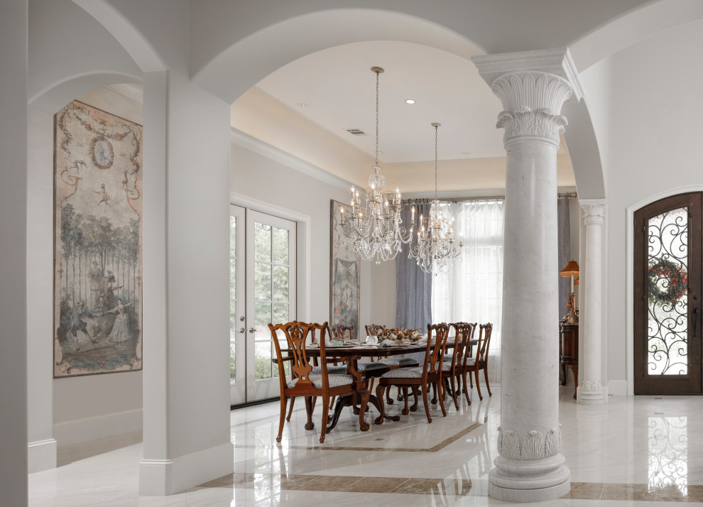 Immagine di una grande sala da pranzo aperta verso il soggiorno con pareti bianche, pavimento in gres porcellanato e pavimento bianco