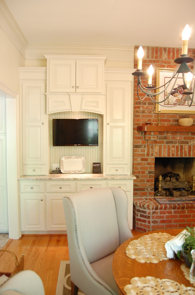 Exemple d'une salle à manger ouverte sur la cuisine chic de taille moyenne avec un sol en bois brun, un sol marron, un mur beige, une cheminée standard et un manteau de cheminée en brique.