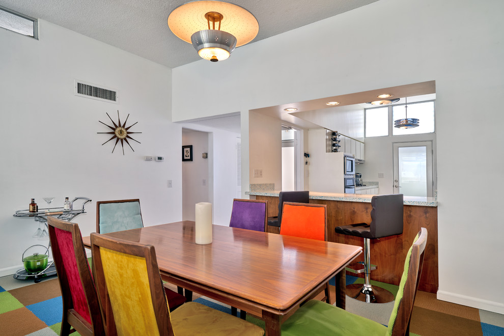 Foto di una sala da pranzo aperta verso la cucina moderna con pareti bianche, moquette e pavimento multicolore