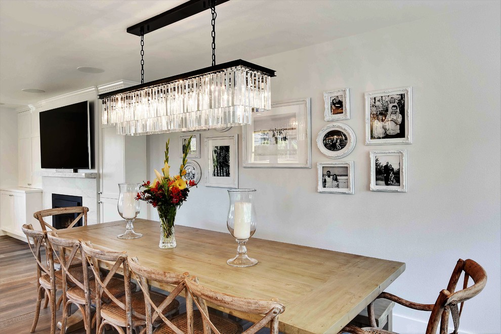 Inspiration pour une salle à manger ouverte sur la cuisine traditionnelle de taille moyenne avec un mur blanc et un sol en bois brun.