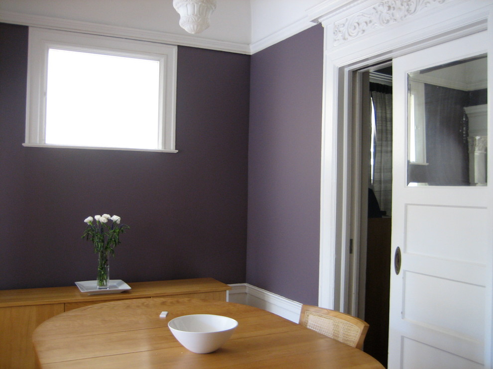 This is an example of a small victorian enclosed dining room in San Francisco with purple walls and light hardwood flooring.