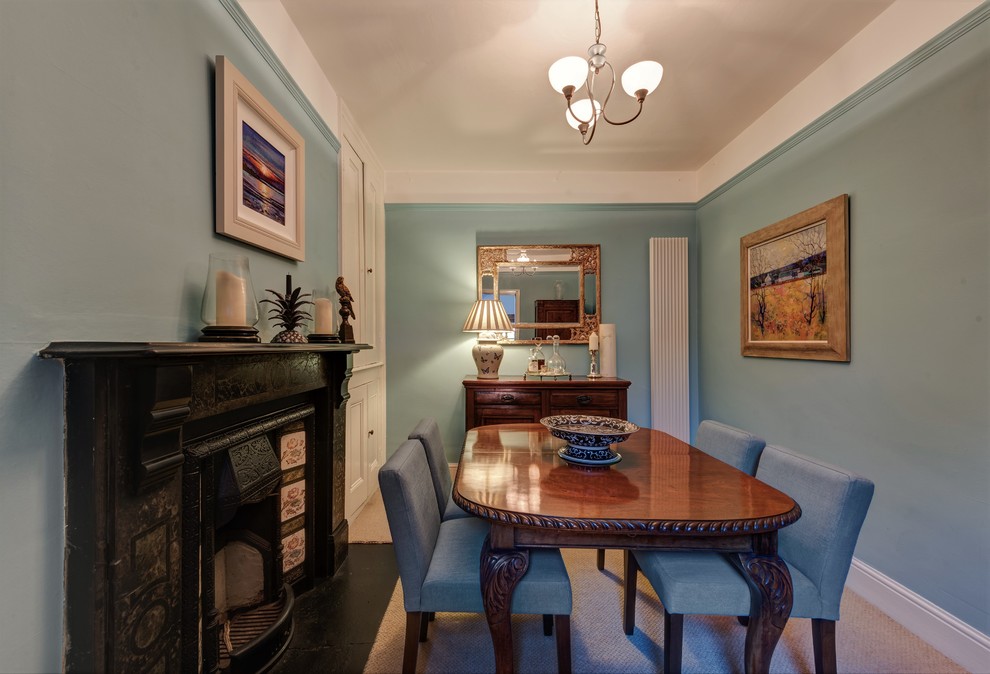 Exemple d'une petite salle à manger nature fermée avec un mur bleu, moquette, une cheminée standard et un manteau de cheminée en pierre.