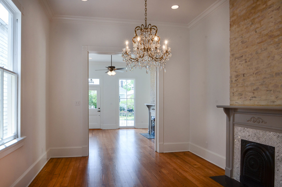 This is an example of a traditional kitchen/dining room in New Orleans with white walls, medium hardwood flooring, a standard fireplace and a wooden fireplace surround.