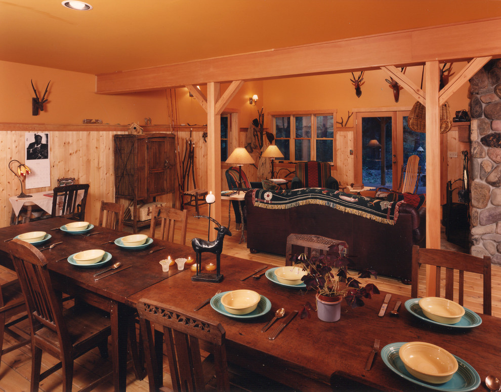 Esempio di una sala da pranzo aperta verso la cucina rustica di medie dimensioni con pareti gialle, parquet chiaro, camino classico e cornice del camino in pietra